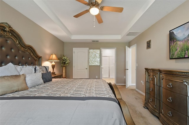 bedroom featuring light colored carpet, a tray ceiling, and ceiling fan