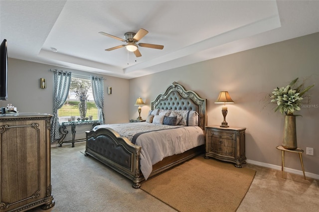 carpeted bedroom with ceiling fan and a raised ceiling