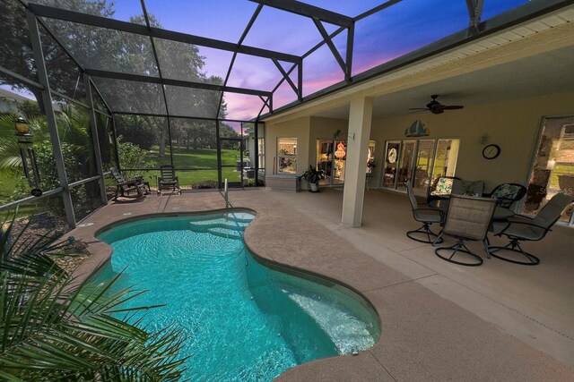 pool at dusk with ceiling fan, a lanai, and a patio