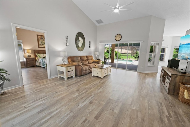 living room with ceiling fan, high vaulted ceiling, and light hardwood / wood-style floors