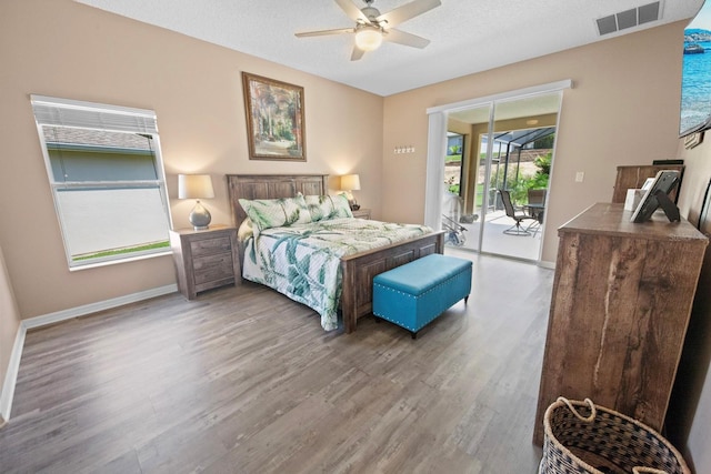 bedroom with multiple windows, access to exterior, hardwood / wood-style floors, and ceiling fan