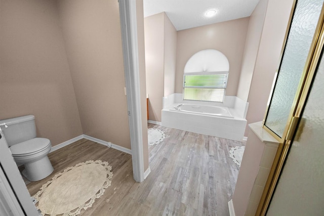 bathroom featuring toilet, a bathing tub, and wood-type flooring