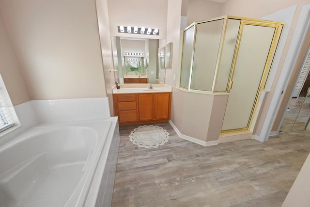 bathroom featuring a shower stall, vanity, a bath, and wood finished floors