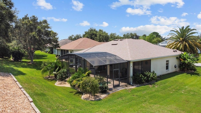 rear view of house featuring a lanai, a yard, and stucco siding