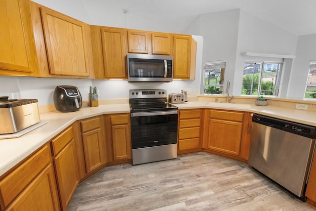 kitchen with appliances with stainless steel finishes, high vaulted ceiling, light hardwood / wood-style floors, and sink