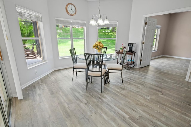 dining area with a towering ceiling, a notable chandelier, and hardwood / wood-style floors