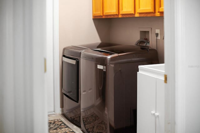 laundry area with washing machine and clothes dryer and cabinets