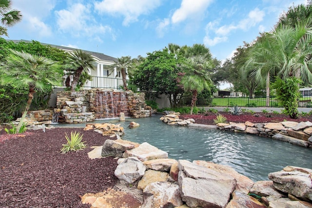 property view of water featuring fence and a garden pond