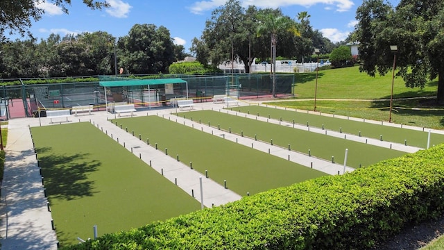 view of home's community with a lawn and tennis court