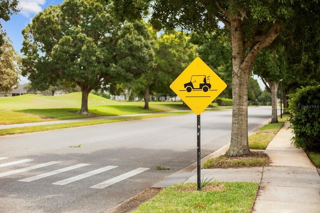 view of road featuring sidewalks, traffic signs, and curbs