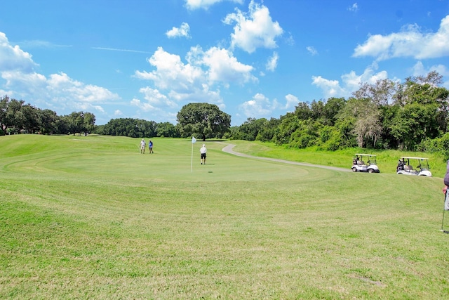 view of home's community featuring view of golf course and a lawn