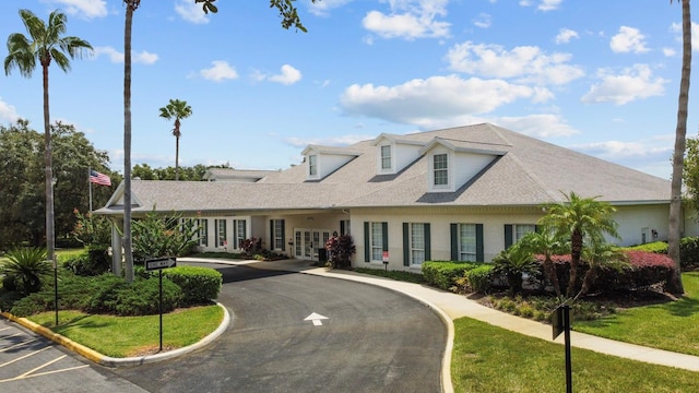 view of front of property featuring driveway, roof with shingles, french doors, and brick siding