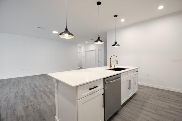 kitchen featuring a center island with sink, stainless steel dishwasher, sink, and hanging light fixtures