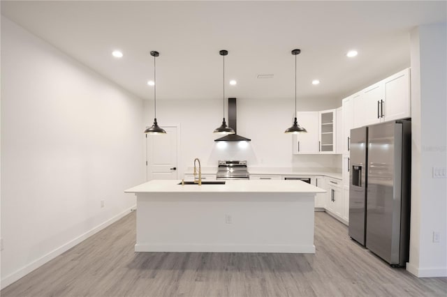 kitchen featuring wall chimney range hood, stainless steel appliances, a kitchen island with sink, and light hardwood / wood-style flooring