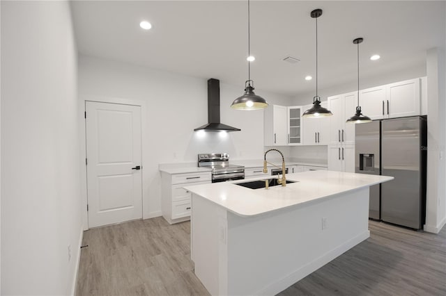 kitchen featuring light wood-type flooring, appliances with stainless steel finishes, sink, wall chimney range hood, and a center island with sink