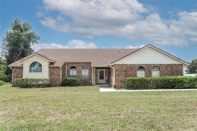 ranch-style home with brick siding, a front lawn, and a shingled roof