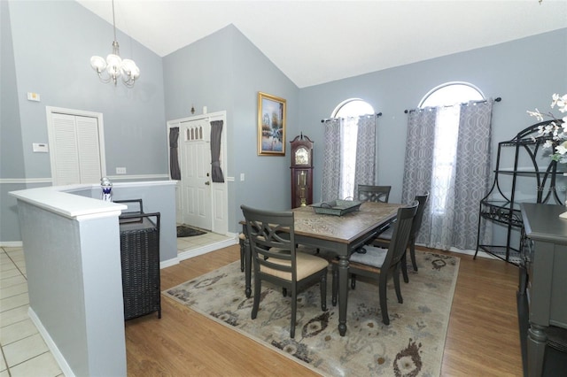 dining space with high vaulted ceiling, an inviting chandelier, and light hardwood / wood-style flooring