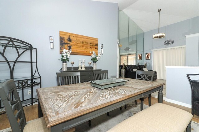 dining space with high vaulted ceiling and hardwood / wood-style flooring