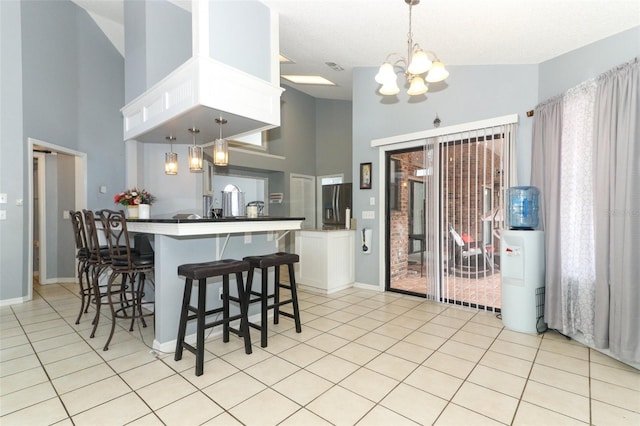 kitchen featuring white cabinetry, light tile patterned flooring, a kitchen breakfast bar, and pendant lighting