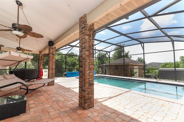 view of swimming pool with ceiling fan, glass enclosure, and a patio area