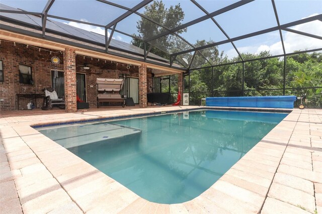 view of pool with glass enclosure and a patio