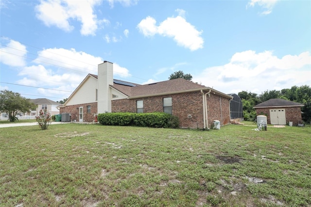 view of property exterior featuring a chimney, central AC, a lawn, and brick siding