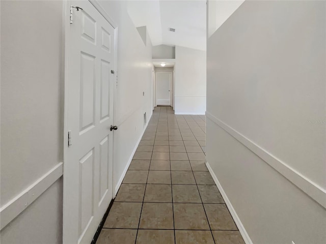 hallway featuring lofted ceiling and tile patterned flooring