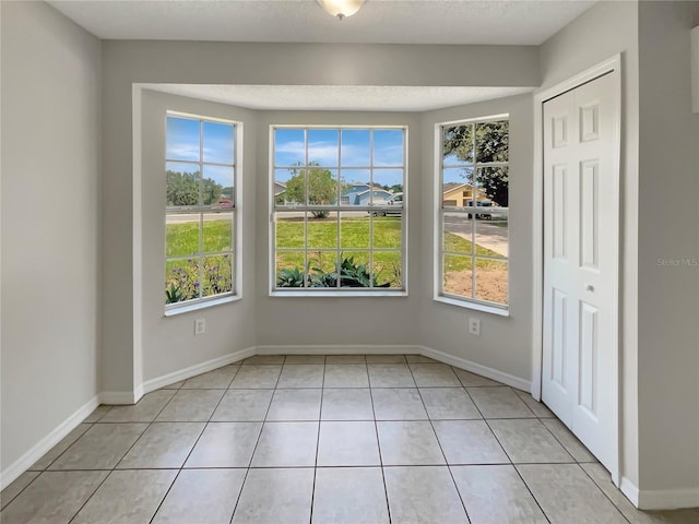 unfurnished dining area with light tile patterned flooring and a textured ceiling