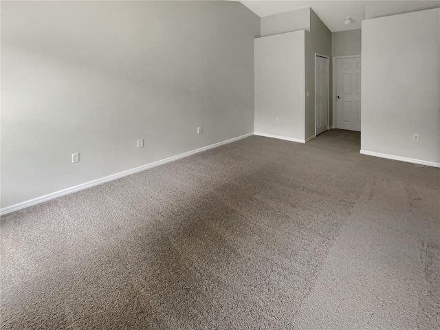 unfurnished room featuring lofted ceiling and dark colored carpet