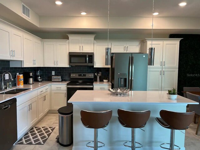 kitchen with black appliances, tasteful backsplash, a breakfast bar, and a sink