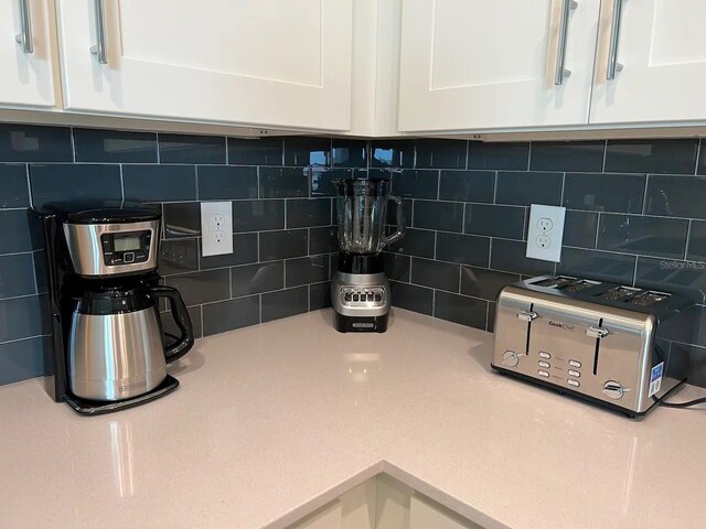 interior details featuring white cabinetry and tasteful backsplash