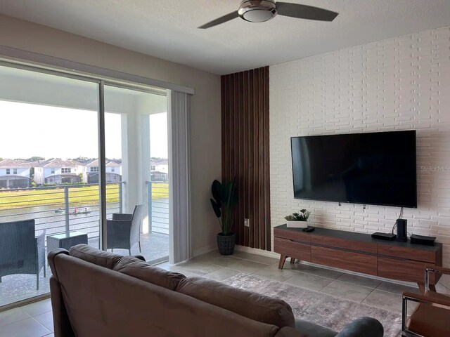 living room featuring a ceiling fan, light tile patterned flooring, and a textured ceiling