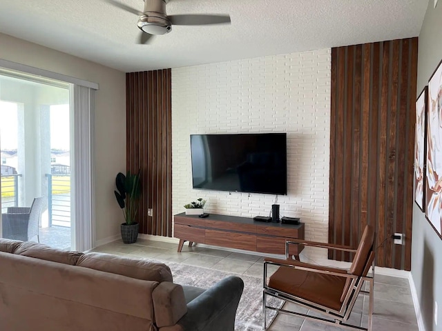 living room with ceiling fan, light tile patterned floors, and a textured ceiling