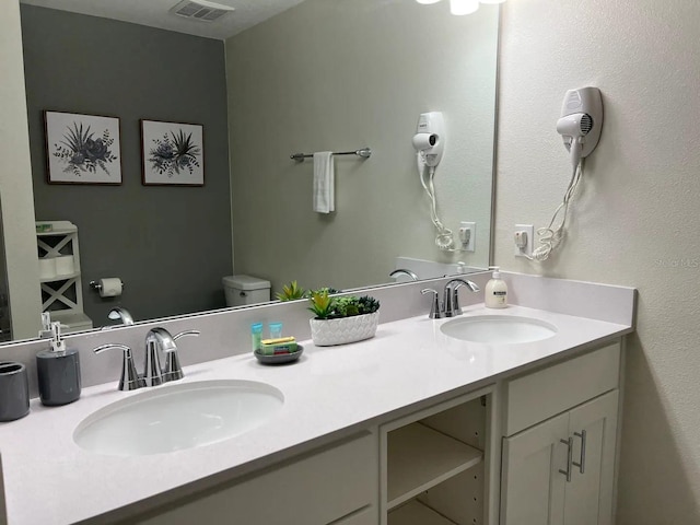 full bathroom featuring double vanity, toilet, and a sink