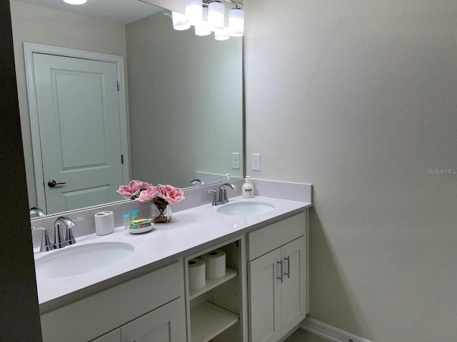 full bathroom featuring double vanity, baseboards, and a sink