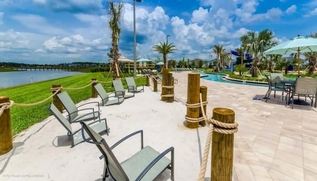 view of property's community featuring a water view, a lawn, a patio area, and a swimming pool