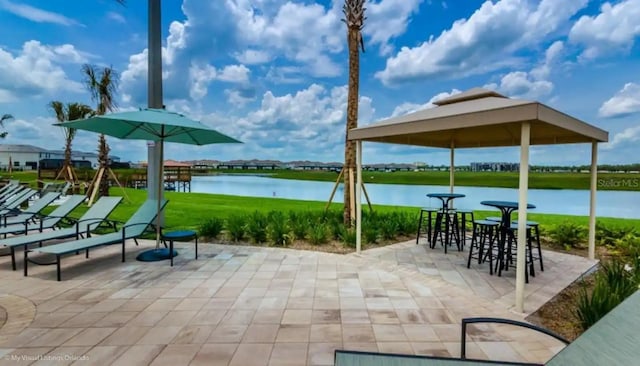 view of community with a patio area, a yard, and a water view