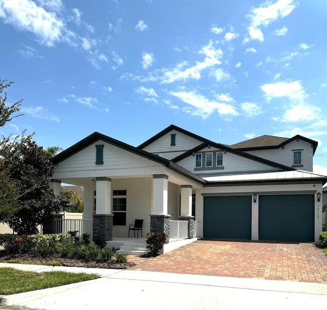 craftsman-style home featuring a porch, an attached garage, stone siding, decorative driveway, and stucco siding