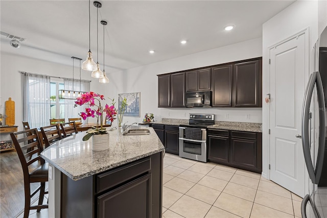 kitchen featuring freestanding refrigerator, a kitchen island with sink, double oven range, black microwave, and a sink