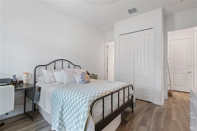 bedroom with a closet, visible vents, and wood finished floors