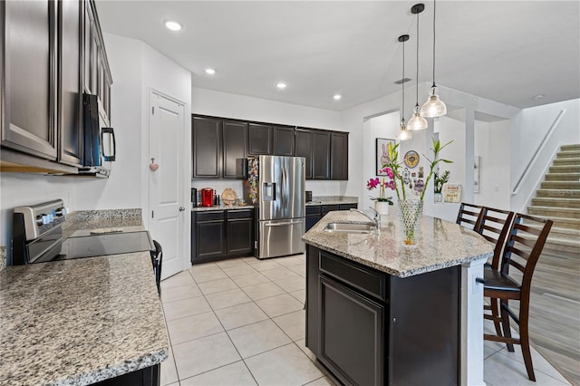 kitchen with a kitchen island with sink, pendant lighting, stainless steel appliances, and a sink