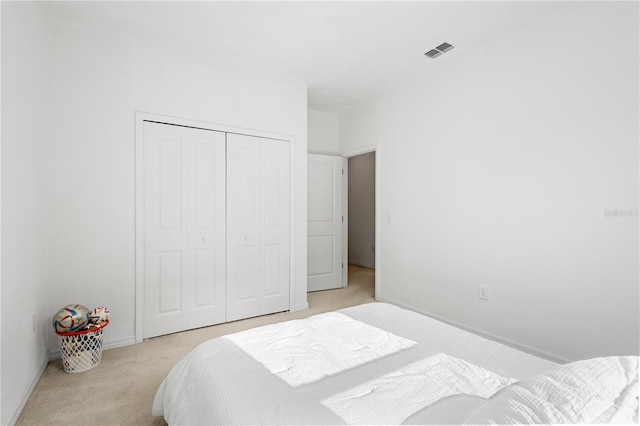 bedroom featuring baseboards, visible vents, a closet, and light colored carpet