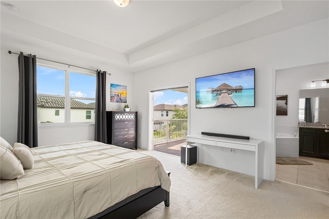 bedroom with light carpet, access to outside, a raised ceiling, and ensuite bathroom