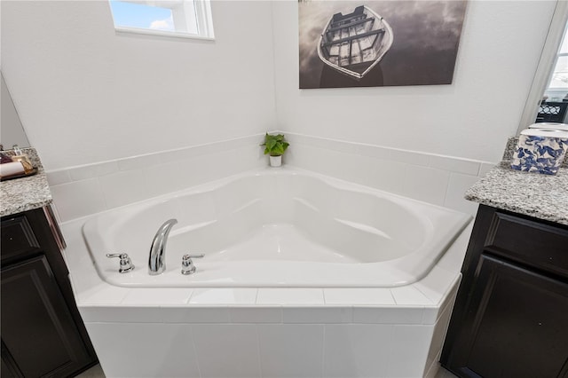 bathroom with a healthy amount of sunlight, a bath, and vanity