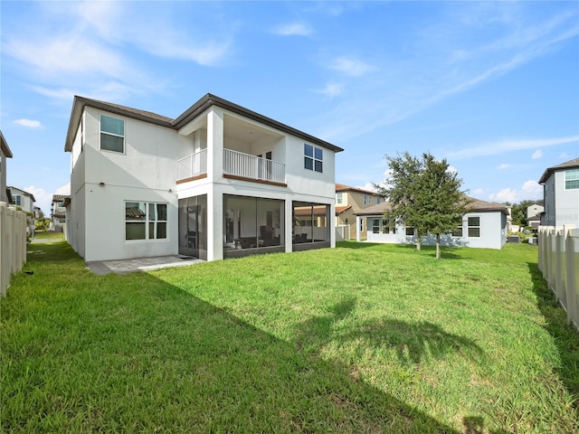 rear view of house with a yard, fence, and stucco siding