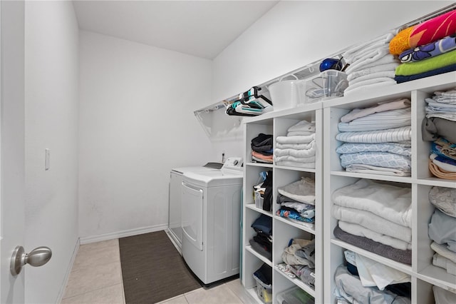 laundry area featuring laundry area, washer and clothes dryer, baseboards, and light tile patterned floors