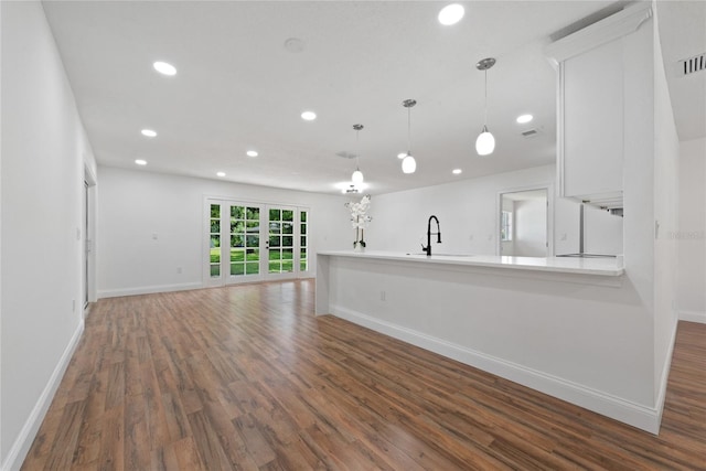 kitchen with white cabinets, hardwood / wood-style floors, sink, kitchen peninsula, and pendant lighting