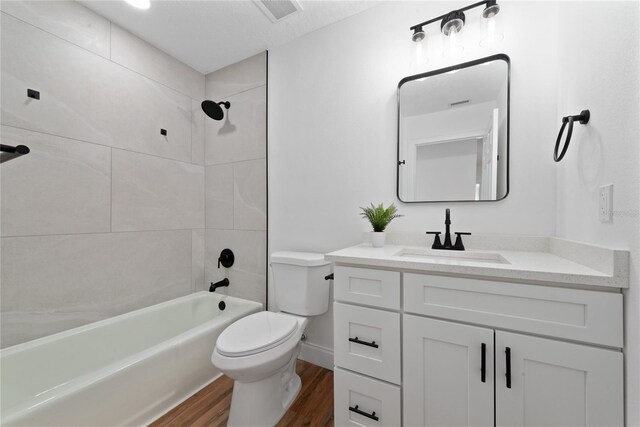 full bathroom with toilet, hardwood / wood-style floors, tiled shower / bath, vanity, and a textured ceiling