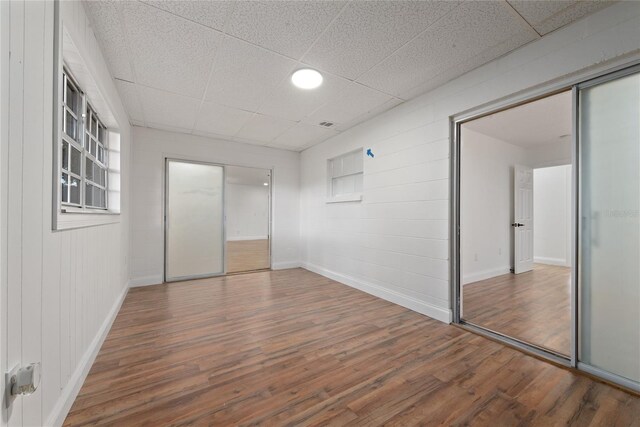 unfurnished bedroom with hardwood / wood-style floors, a paneled ceiling, and a closet