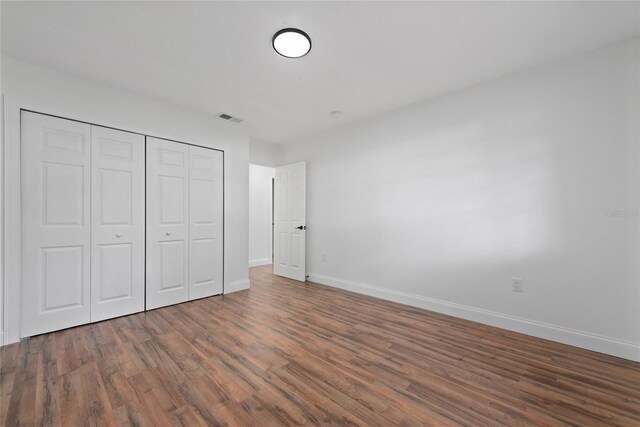 unfurnished bedroom featuring dark hardwood / wood-style floors and a closet